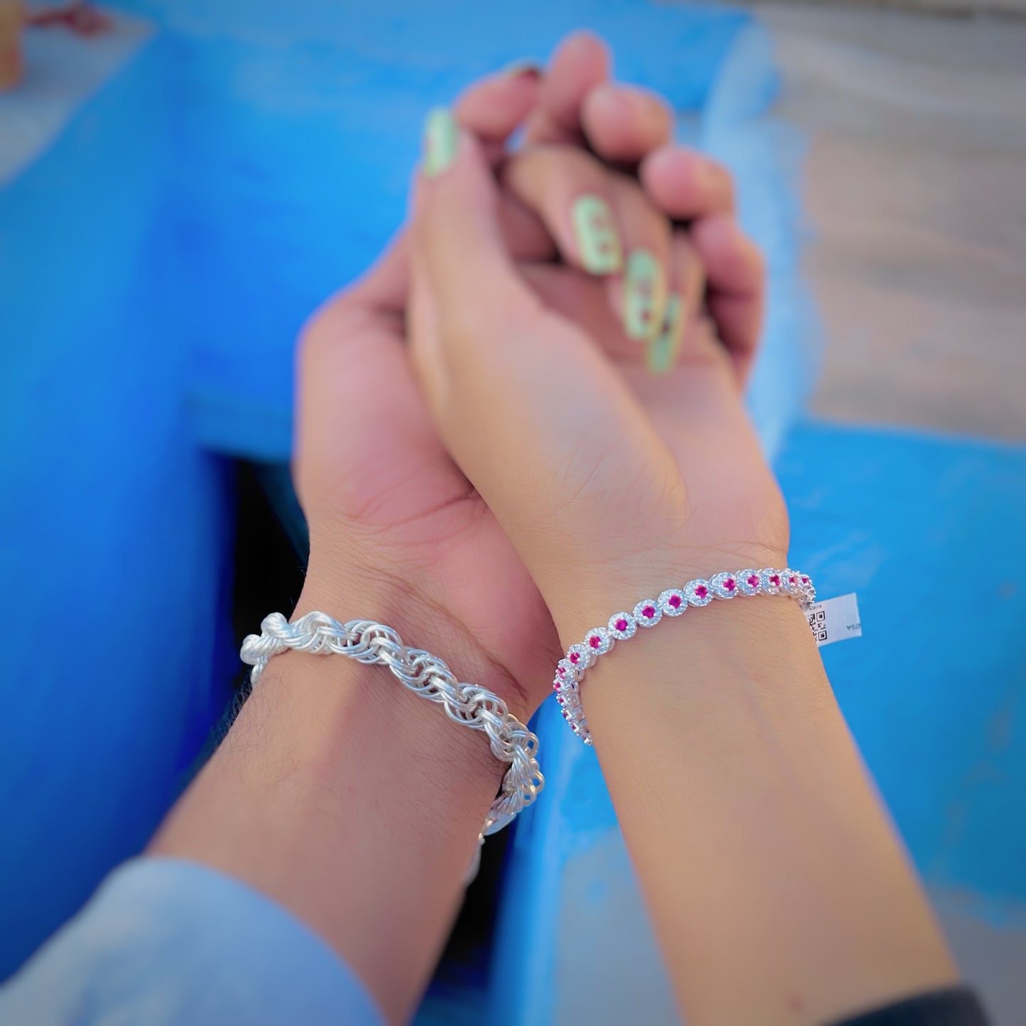 Stylish silver bracelet set featuring boy's curly chain and girl's pink stone bracelet.