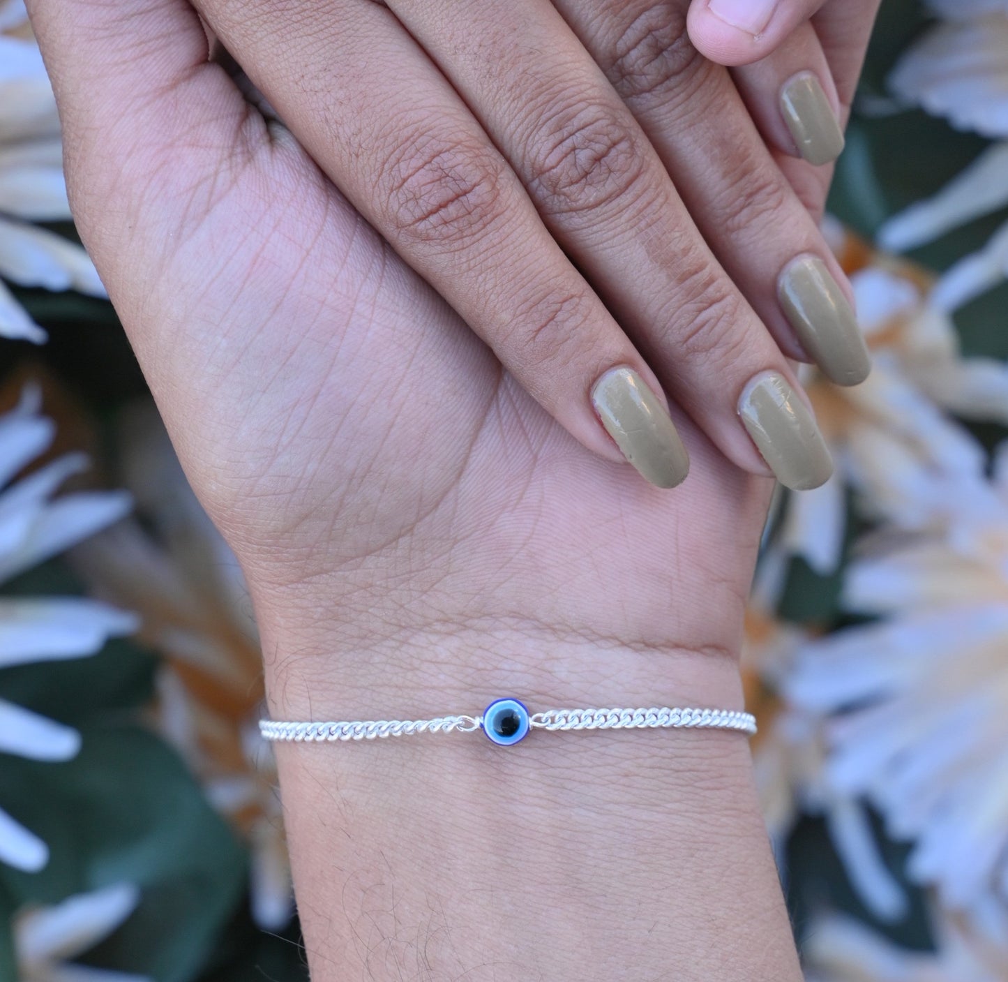 Silver bracelet with blue evil eye charm for fashionable protection.